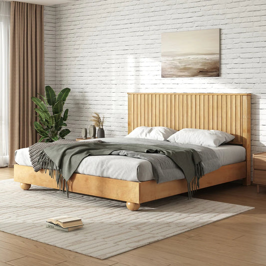 Wooden bed in a bedroom with a plant and painting on the wall.