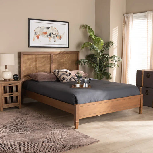 Wooden bed in a bedroom with a plant and framed artwork on the wall.