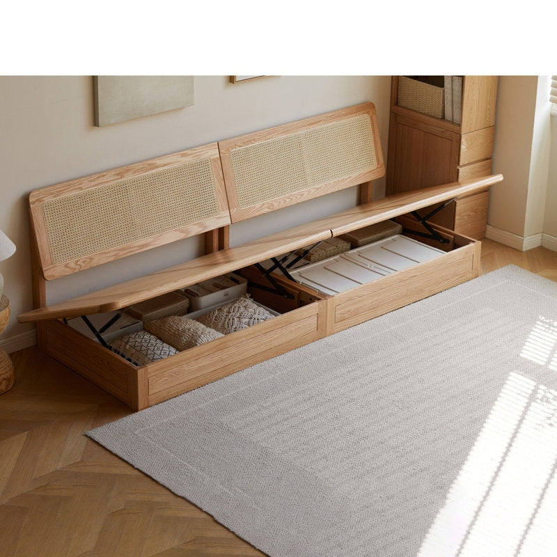 Wooden bed with storage drawers and wicker headboard in a room setting.