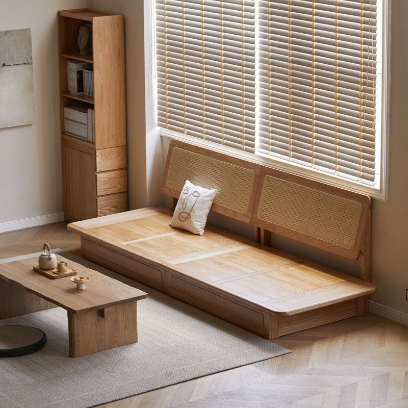 Wooden bed with wicker headboard in a room with a window and small table.
