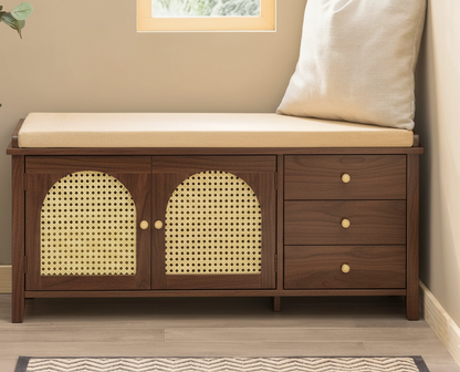 Wooden bench with cushioned seat and rattan accents in a room setting.
