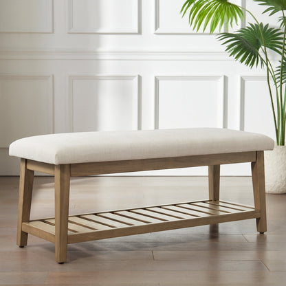 Wooden bench with white cushion on a wooden floor with a plant in the background