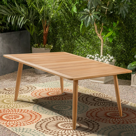 Wooden outdoor table with a patterned rug and plants in the background