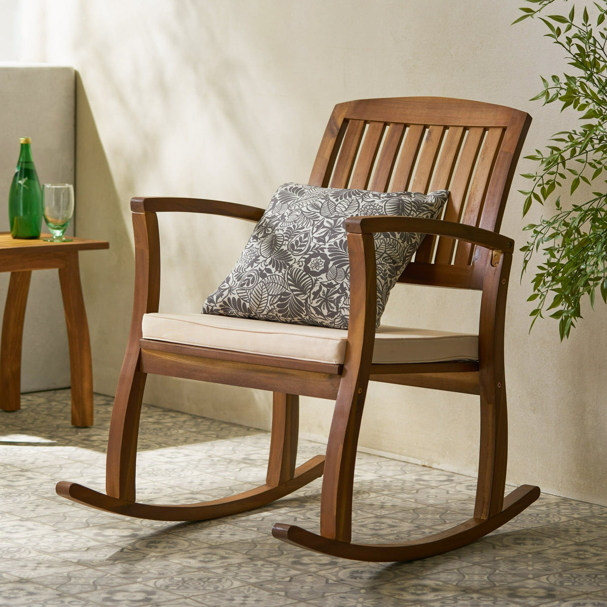 Wooden rocking chair with a cushion and decorative pillow in a room setting.