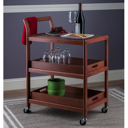 Wooden serving cart with wine glasses, plates, and a bottle against a purple wall.
