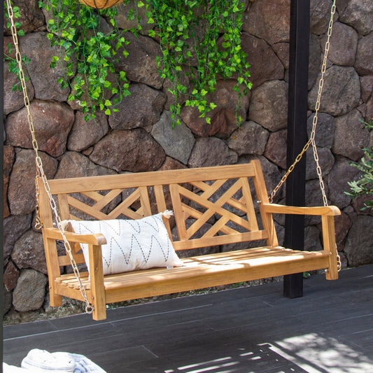 Wooden swing with a cushion against a stone wall