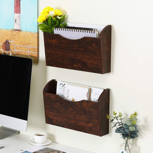 Wooden wall-mounted magazine rack with books and a notebook on a white wall above a desk.
