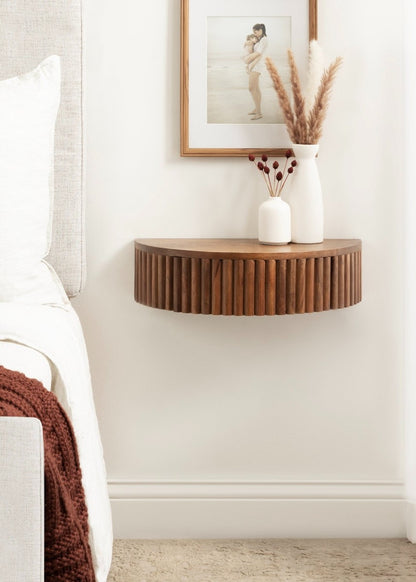 Wooden wall-mounted shelf in a bedroom with decorative items.