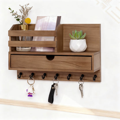 Wooden wall-mounted shelf with a drawer and hooks, holding decorative items.