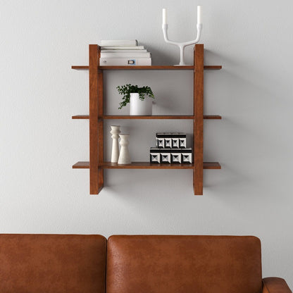 Wooden wall shelf with decorative items against a light gray wall, brown sofa in foreground.