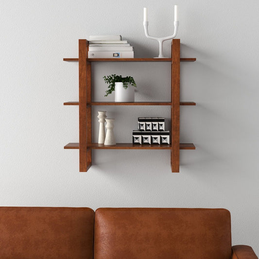 Wooden wall shelf with decorative items against a light gray wall, brown sofa in foreground.