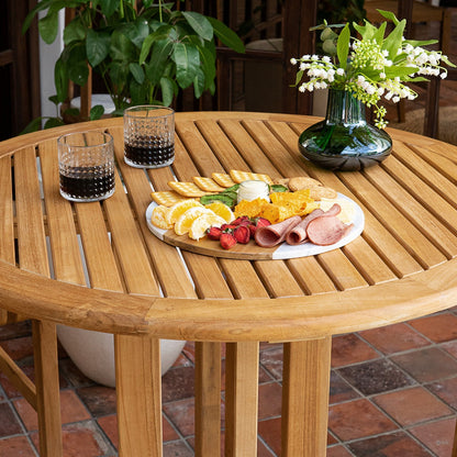 Wooden table with a plate of food and glasses on a patio
