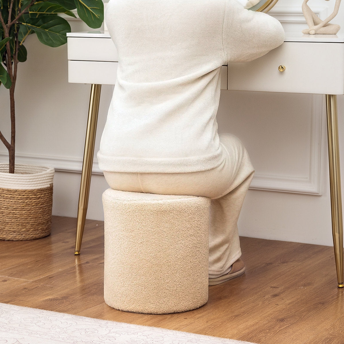 Person using a beige footstool in a home setting with a desk and plant in the background.