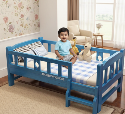 Child sitting on a blue children's bed in a room with floral wallpaper and a window.