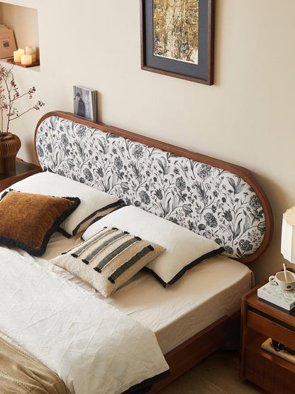 Bedroom with a floral-patterned headboard and decorative pillows.