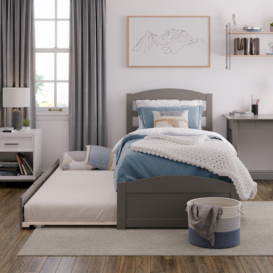 Bedroom with gray bed frame, blue bedding, and a desk with books.