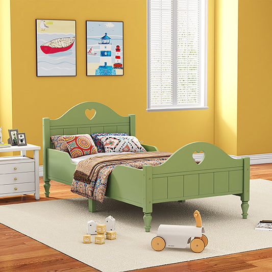 A green, handcrafted solid Sheesham wood classic bed for kids with a mattress, placed in a room with yellow walls and children's toys around.