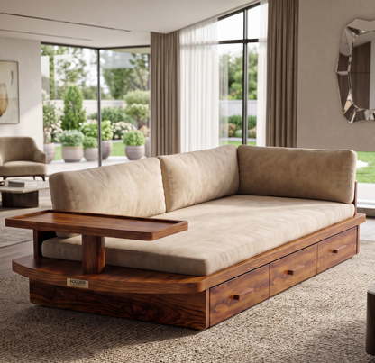 A modern wooden daybed with a thick beige upholstered cushion and matching back cushions, set in a contemporary living room with large windows and a garden view.