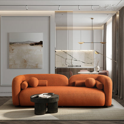 Modern living room with an orange sofa, black coffee table, and abstract art on the wall.