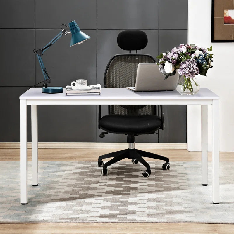 Modern office desk with laptop, lamp, and flowers in a stylish room.