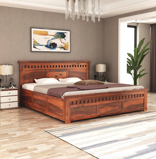 A solid Sheesham wood standard bed with box storage, finished in a natural honey color, placed in a room with a mattress on it.