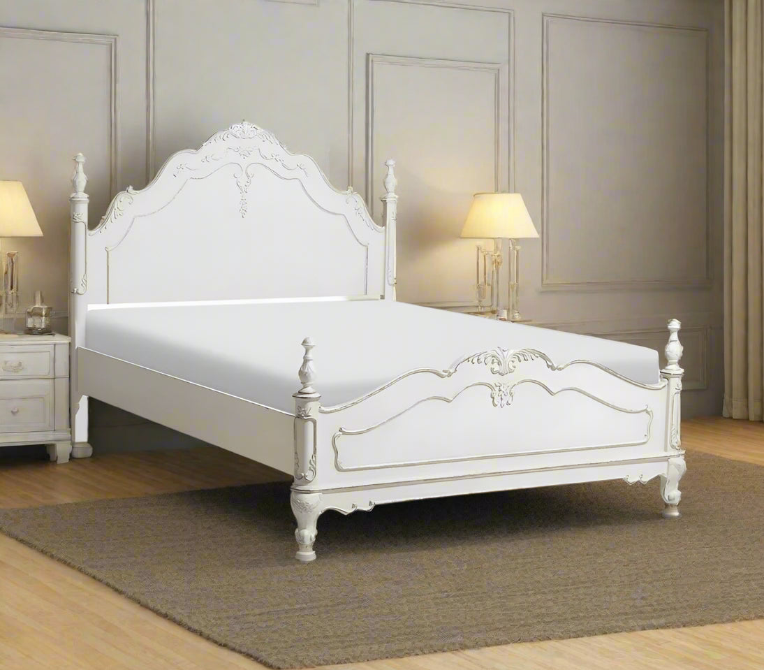 A white, Victorian-style poster bed with a mattress, bedside table, and ornate detailing in a room setting.