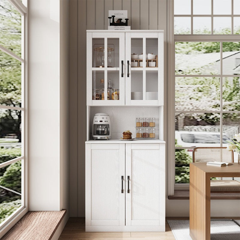 White kitchen cabinet with glass doors in a bright room with large windows.