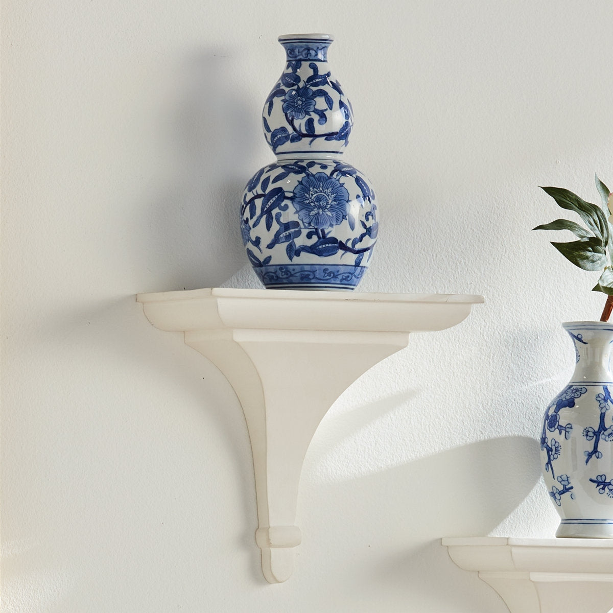 Blue and white floral-patterned vases on a white shelf against a light gray wall.