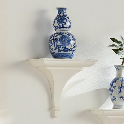 Blue and white floral-patterned vases on a white shelf against a light gray wall.