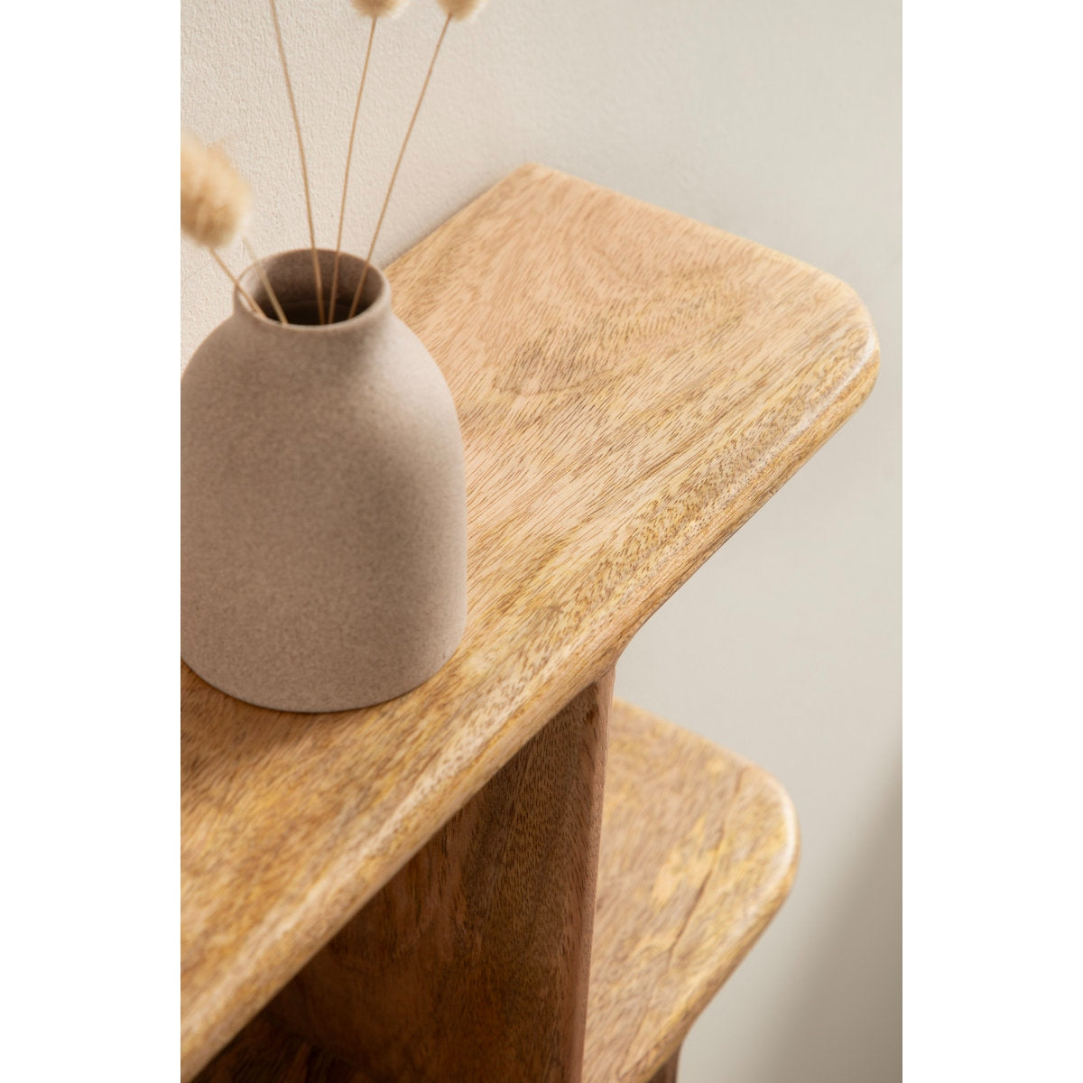 Beige ceramic vase with dried plants on a wooden surface