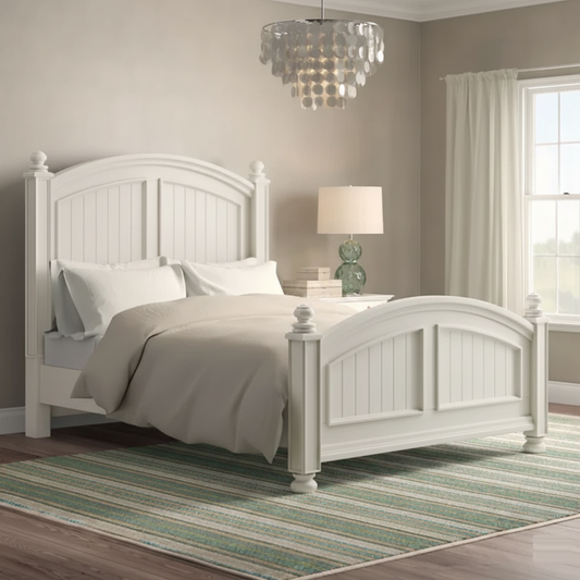 White bedroom with a bed, lamp, and striped rug.