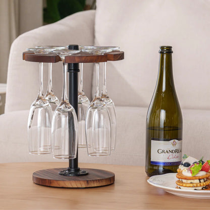 A wooden wine glass stand with metal supports, capable of holding six wine glasses, positioned on a table with a bottle and some fruits in the background.