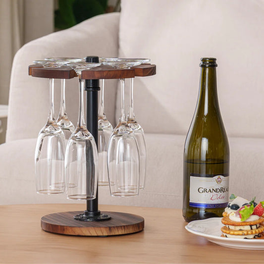 A wooden wine glass stand with metal supports, capable of holding six wine glasses, positioned on a table with a bottle and some fruits in the background.