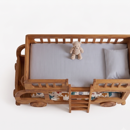 Wooden crib with striped mattress and teddy bear on a white background