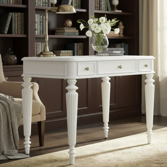 White console table with drawers in a room with bookshelves and a chair.