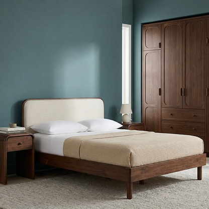 Wooden bed with beige bedding in a bedroom with a wardrobe and lamp.