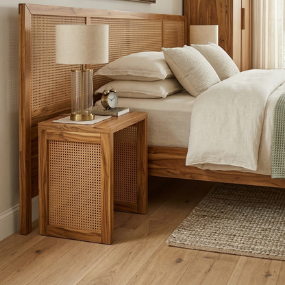 Wooden bed with wicker headboard and nightstand in a bedroom setting.