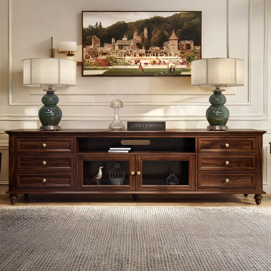 Wooden entertainment console with two lamps and a painting in a living room setting.