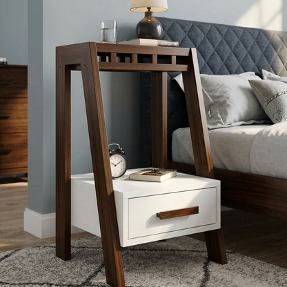 Wooden nightstand with white drawer next to a bed with gray bedding.