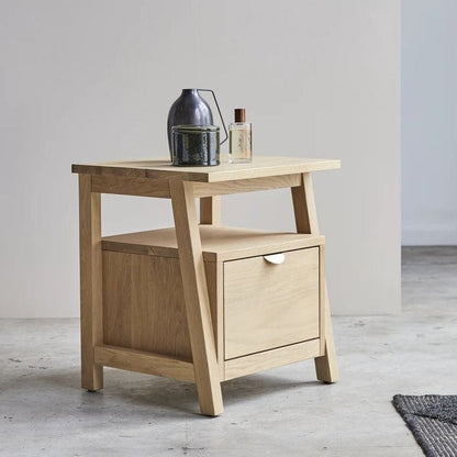 Wooden side table with a drawer and decorative items on a light gray background