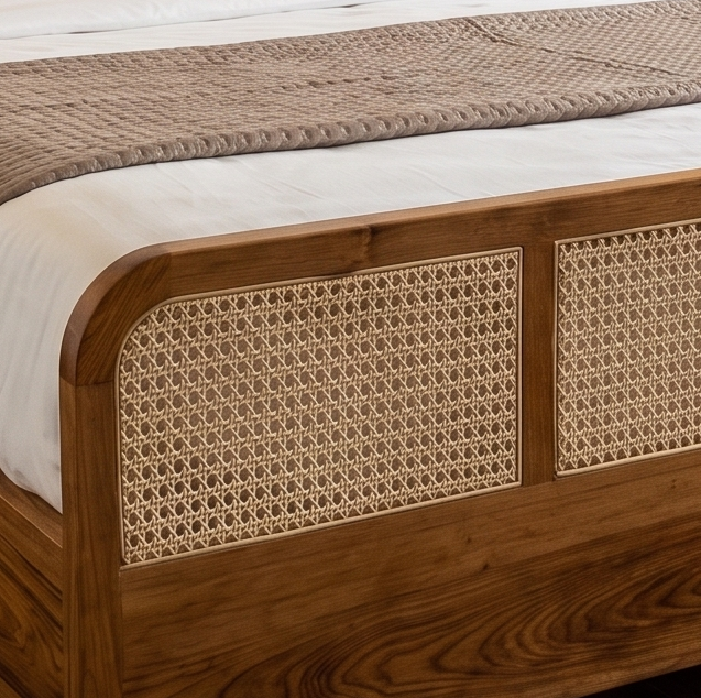 Close-up of a wooden bed frame with woven cane panels, dressed in white bedding and a textured beige runner.