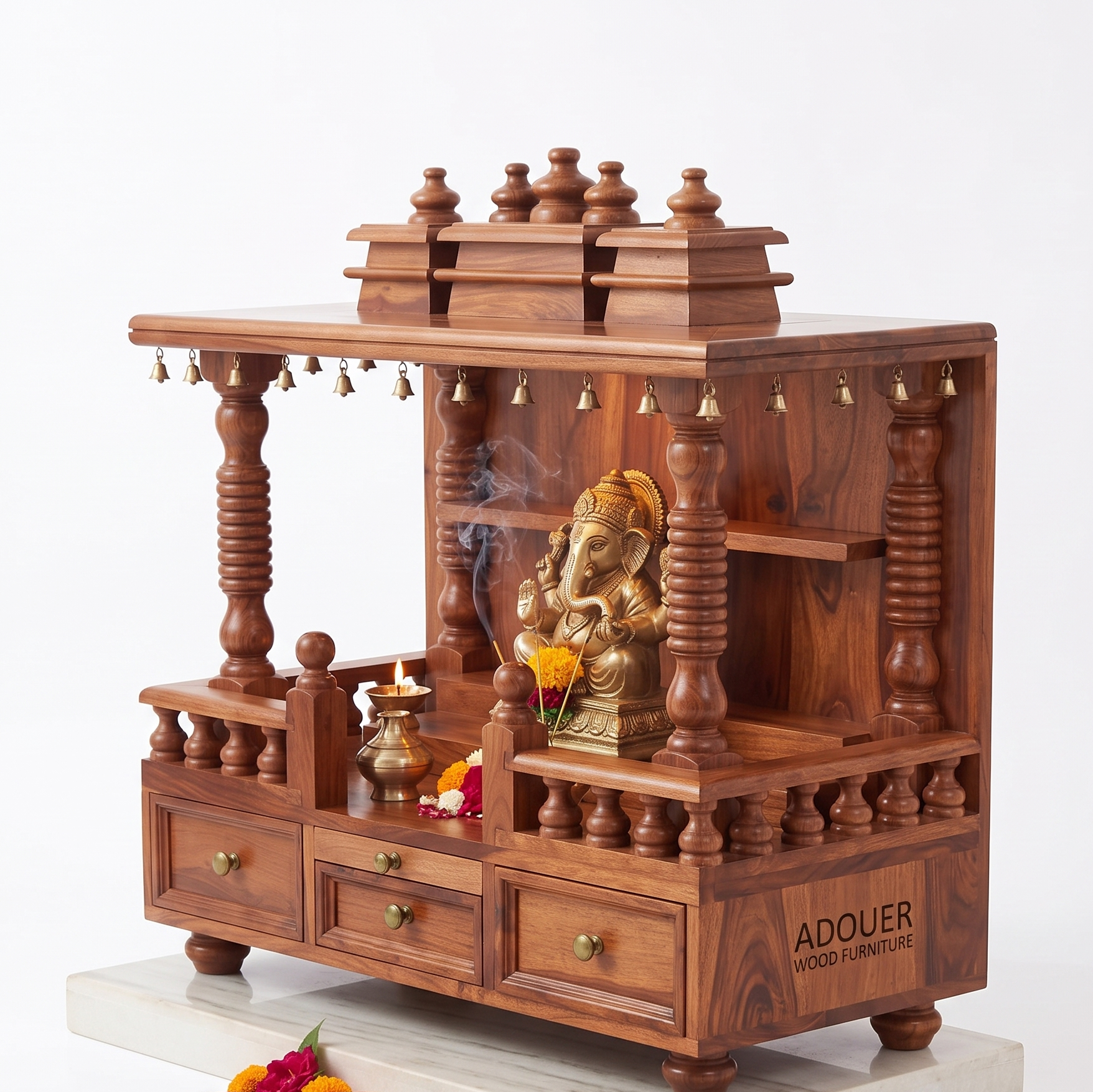 A wooden Ganesh idol display stand or miniature altar made of rich reddish-brown wood, featuring carved pillars, tiered shelves, small hanging bells, and three drawers. A brass Ganesh statue sits inside, with a diya and flowers arranged on and around it.